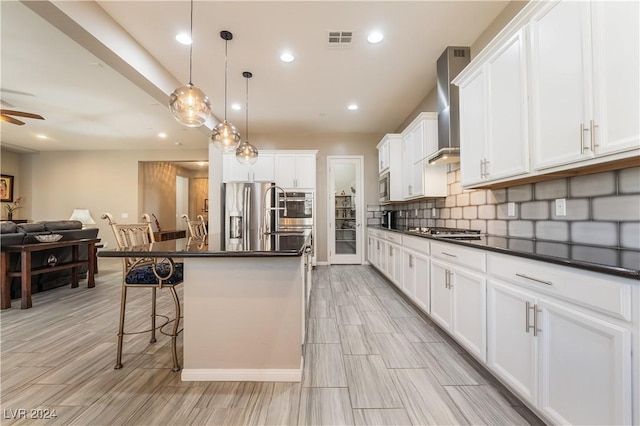 kitchen with a breakfast bar, pendant lighting, white cabinets, stainless steel appliances, and a center island with sink