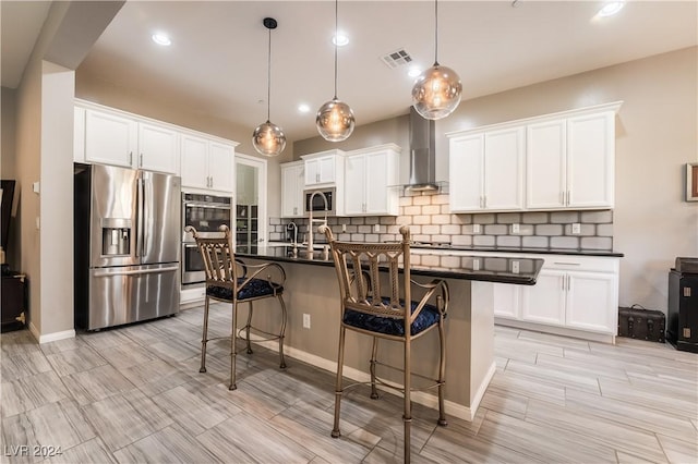 kitchen featuring dark countertops, visible vents, wall chimney range hood, a kitchen bar, and stainless steel appliances