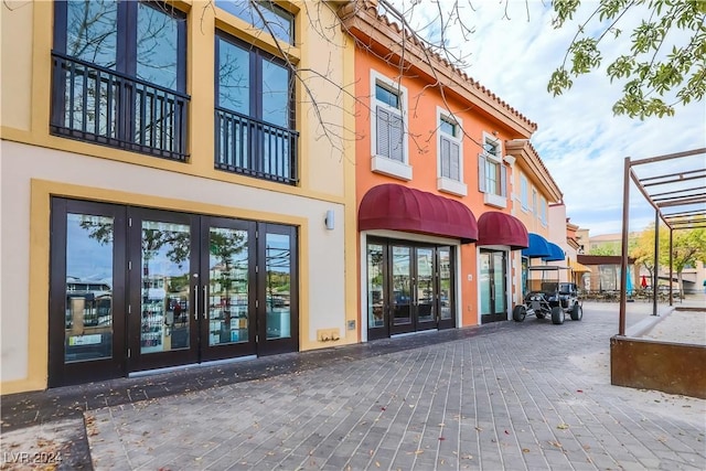 entrance to property with a tile roof, french doors, and stucco siding