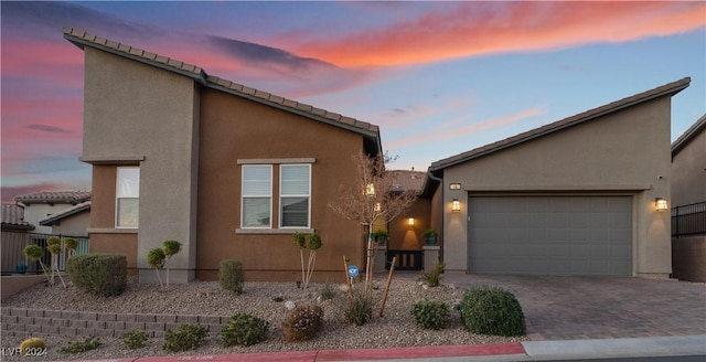 view of front of property featuring a garage, decorative driveway, and stucco siding