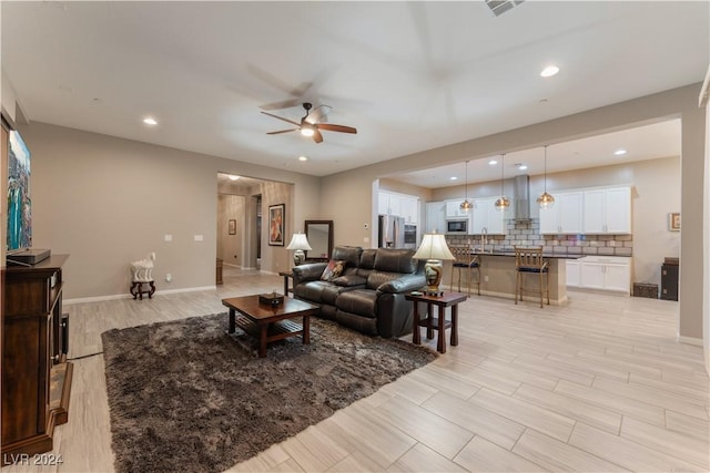 living room featuring light wood finished floors, recessed lighting, and baseboards