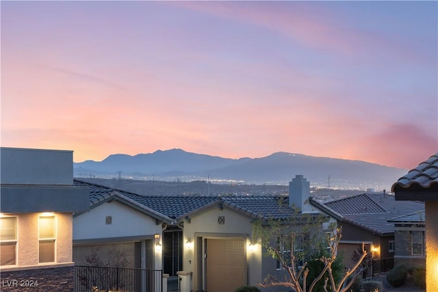 view of front of house featuring a tiled roof, a mountain view, an attached garage, and stucco siding