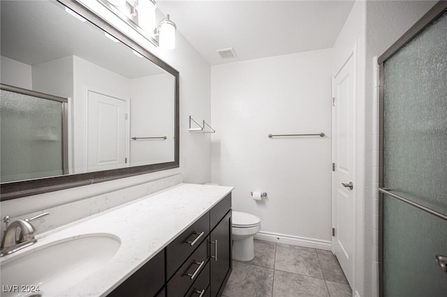 bathroom featuring tile patterned flooring, vanity, a shower with shower door, and toilet