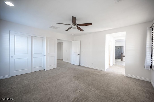 unfurnished bedroom featuring ceiling fan, light carpet, and a closet