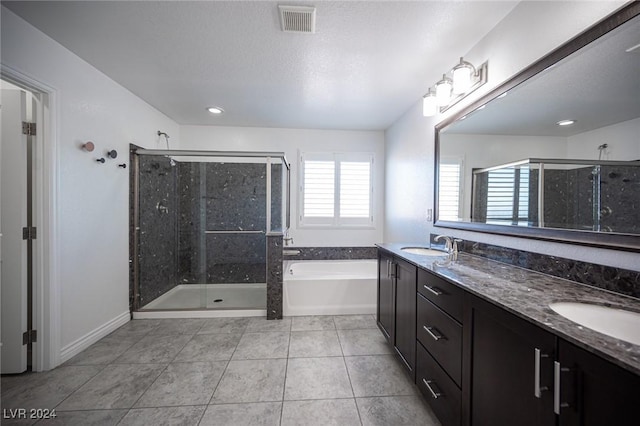 bathroom featuring tile patterned floors, vanity, separate shower and tub, and a textured ceiling