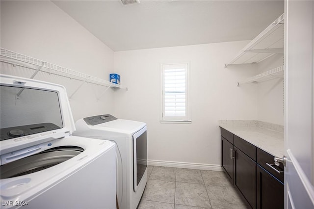 washroom with cabinets, light tile patterned floors, and washer and clothes dryer