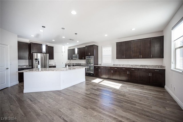 kitchen featuring decorative light fixtures, a kitchen island with sink, dark wood-type flooring, and appliances with stainless steel finishes