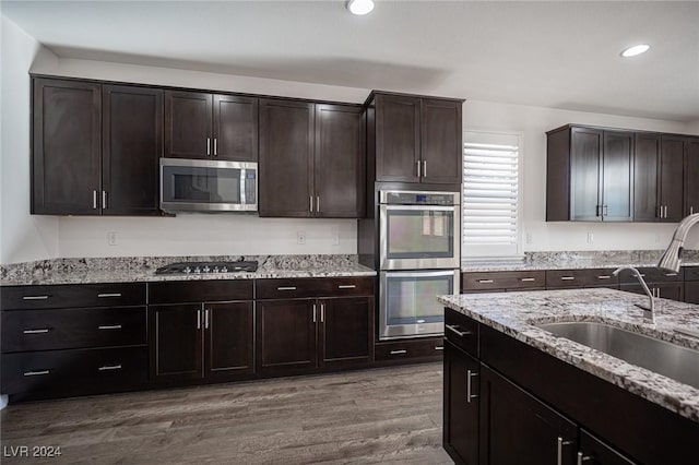 kitchen featuring wood-type flooring, dark brown cabinetry, stainless steel appliances, and sink