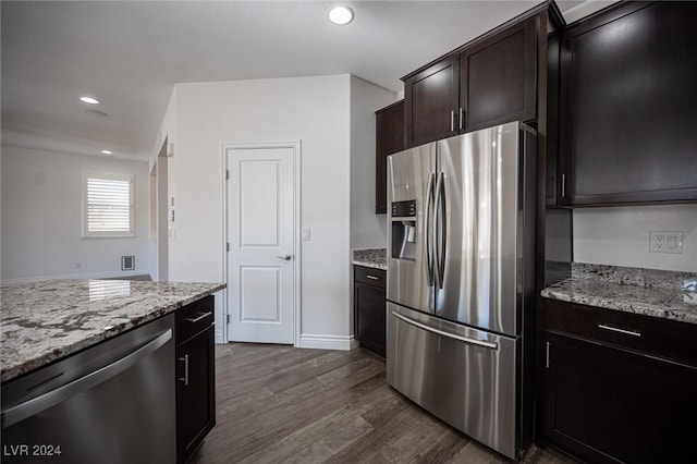 kitchen with dark brown cabinets, dark hardwood / wood-style flooring, light stone countertops, and appliances with stainless steel finishes