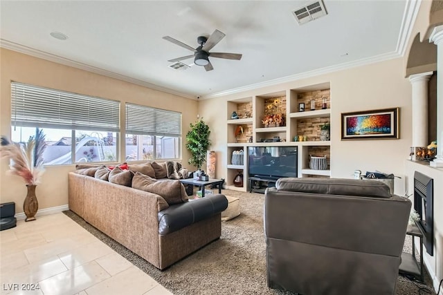 tiled living room with decorative columns, ceiling fan, crown molding, built in features, and a fireplace