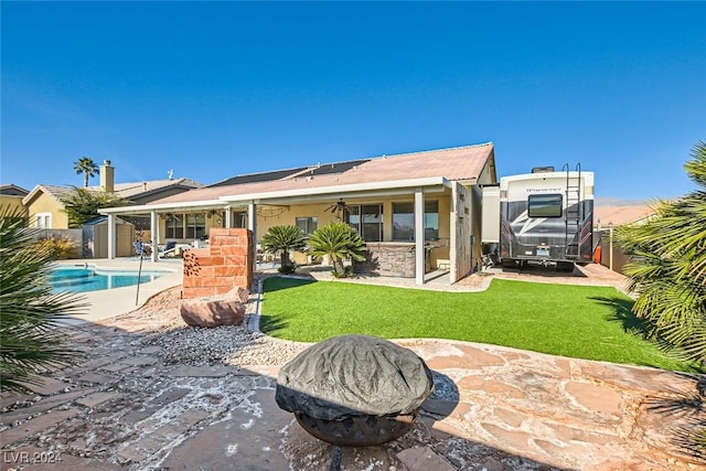 rear view of property featuring a patio area, ceiling fan, a yard, and a storage shed