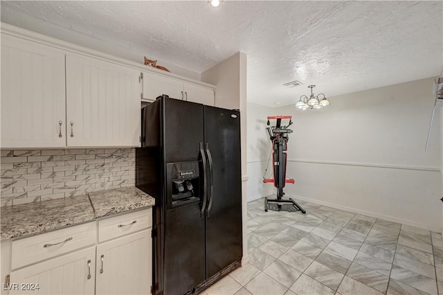 kitchen featuring a notable chandelier, black fridge with ice dispenser, pendant lighting, white cabinets, and light stone counters