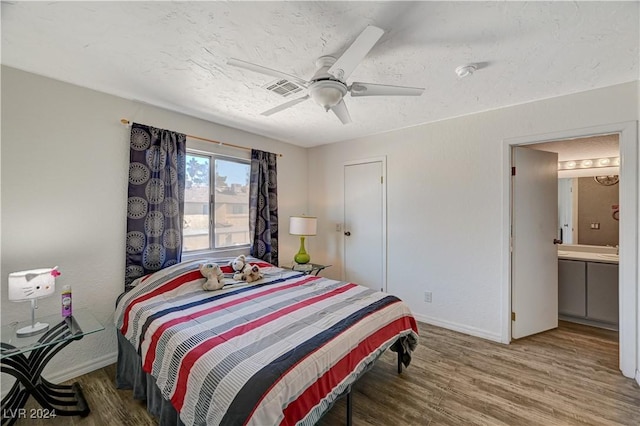 bedroom with a textured ceiling, ceiling fan, hardwood / wood-style flooring, and ensuite bath