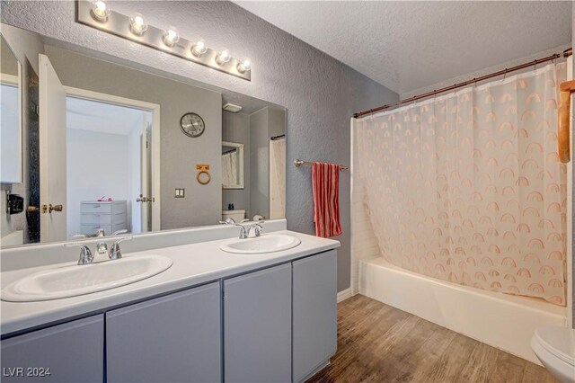 full bathroom with toilet, vanity, shower / bath combo, hardwood / wood-style flooring, and a textured ceiling