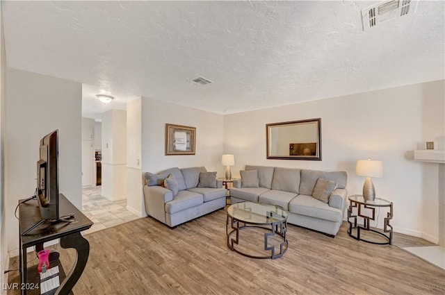 living room with a textured ceiling and light hardwood / wood-style flooring