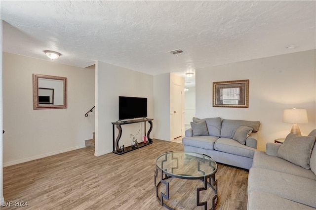 living room with a textured ceiling and light hardwood / wood-style floors