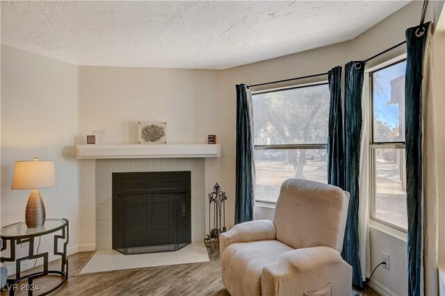 sitting room featuring light hardwood / wood-style floors, a textured ceiling, and a tiled fireplace