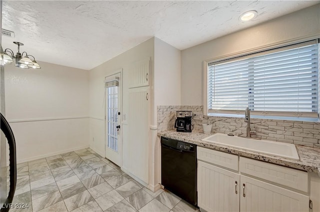 kitchen featuring black dishwasher, sink, white cabinetry, and decorative light fixtures