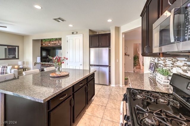 kitchen featuring stone counters, decorative backsplash, light tile patterned floors, dark brown cabinetry, and stainless steel appliances