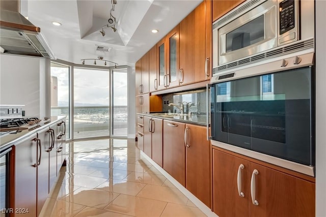 kitchen with track lighting, stainless steel appliances, extractor fan, sink, and light tile patterned flooring