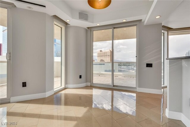 empty room with light tile patterned floors and a healthy amount of sunlight