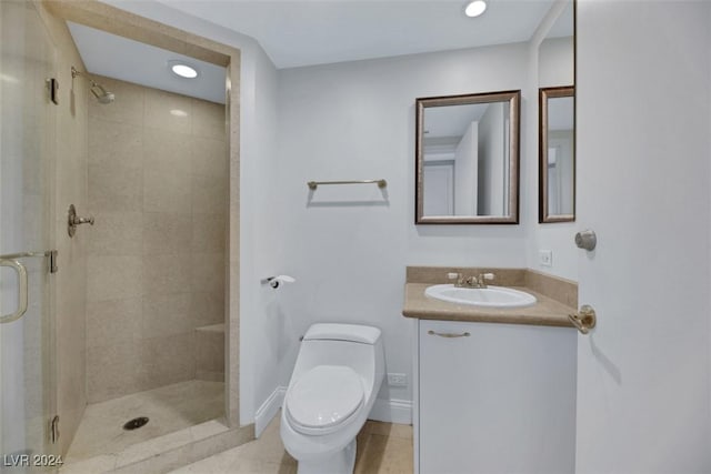 bathroom featuring tile patterned flooring, vanity, toilet, and a shower with shower door