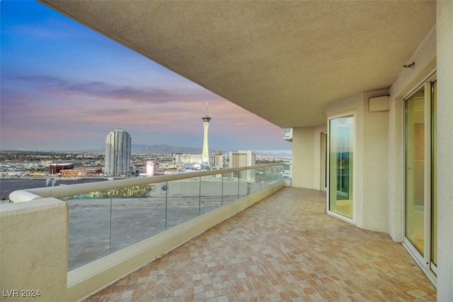 balcony at dusk featuring a view of city