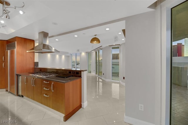 kitchen with wall chimney exhaust hood, light tile patterned floors, stainless steel appliances, and a wealth of natural light