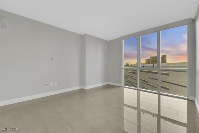 unfurnished room with floor to ceiling windows and tile patterned flooring