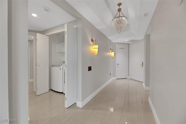 hall with a notable chandelier, washing machine and dryer, and light tile patterned floors