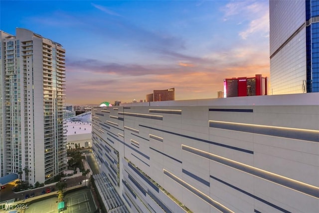 balcony at dusk featuring a view of city