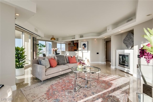 living room featuring a glass covered fireplace, visible vents, baseboards, and recessed lighting