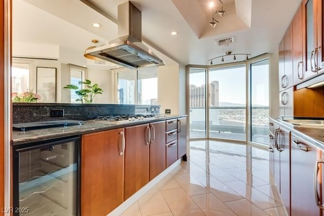 kitchen with wine cooler, stainless steel gas cooktop, island exhaust hood, light tile patterned floors, and visible vents