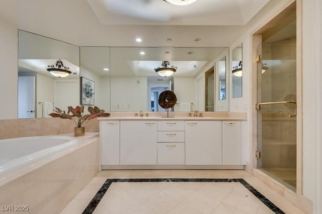 bathroom featuring double vanity, a stall shower, a raised ceiling, a garden tub, and a sink