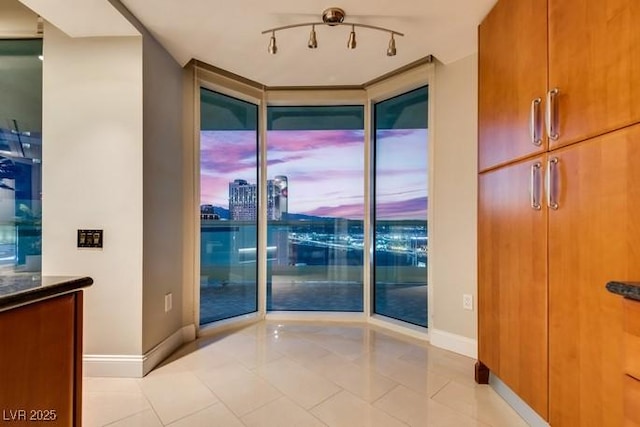 interior space featuring rail lighting, light tile patterned flooring, and baseboards