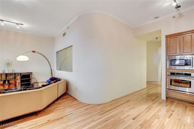 kitchen with light wood-type flooring, ornamental molding, and appliances with stainless steel finishes