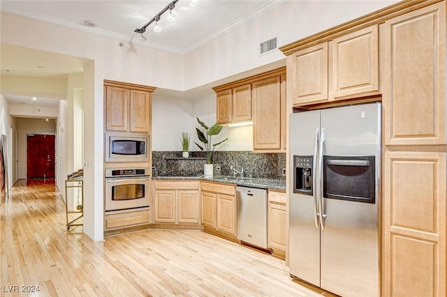 kitchen with light brown cabinetry, stainless steel appliances, light hardwood / wood-style flooring, and dark stone counters