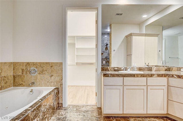 bathroom with vanity and tiled tub