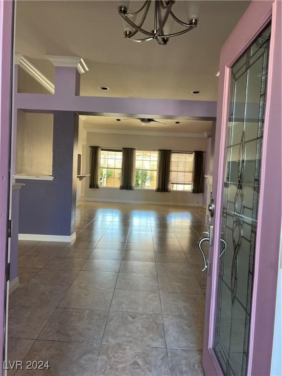 hall with tile patterned floors, ornamental molding, and an inviting chandelier