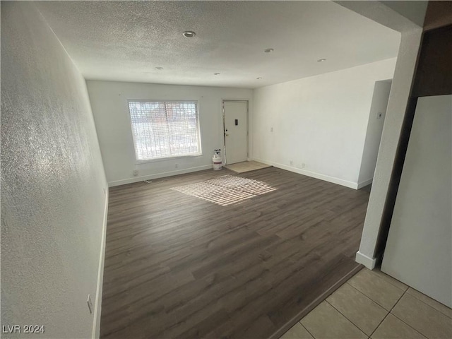 empty room with wood-type flooring and a textured ceiling