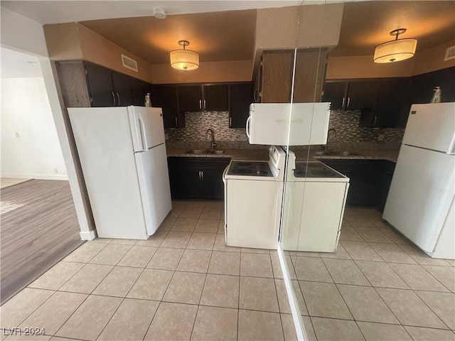 kitchen featuring white appliances, sink, tasteful backsplash, dark brown cabinets, and washer / dryer