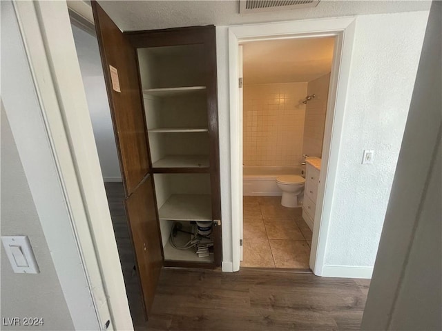 interior space featuring tiled shower / bath, hardwood / wood-style floors, vanity, and toilet