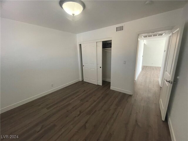 unfurnished bedroom with a closet and dark hardwood / wood-style flooring