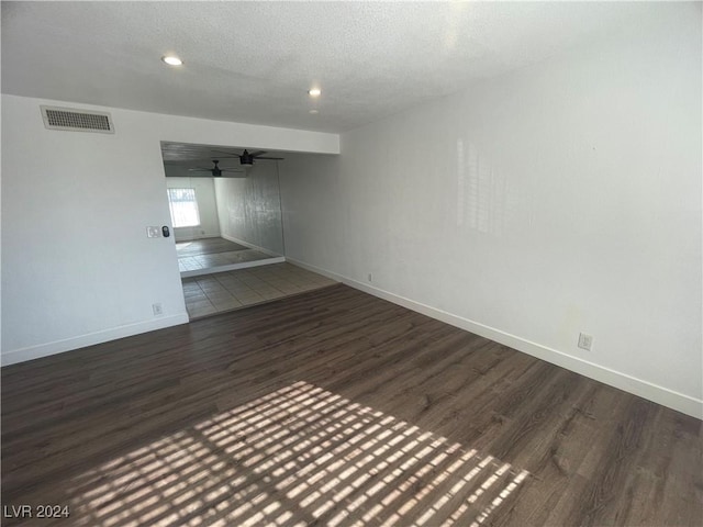 empty room featuring dark hardwood / wood-style floors, ceiling fan, and a textured ceiling