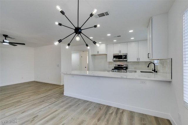 kitchen featuring white cabinets, light hardwood / wood-style floors, kitchen peninsula, and stainless steel appliances