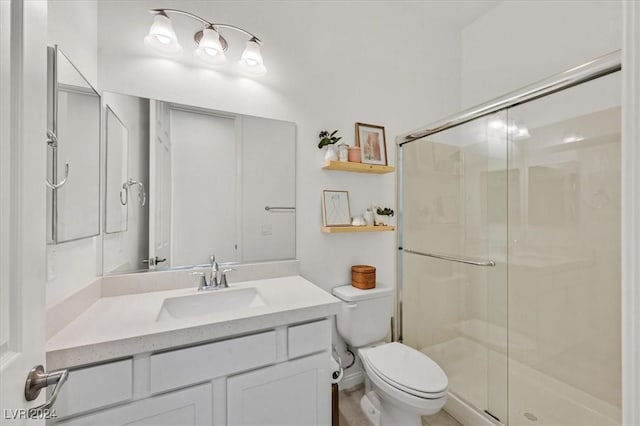 bathroom with vanity, toilet, and a shower with door