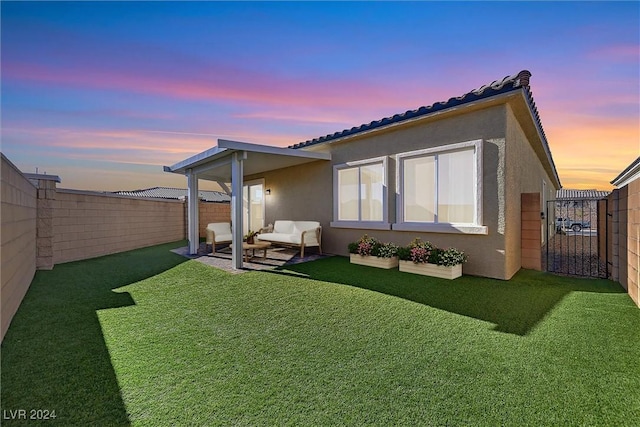 back house at dusk featuring a lawn