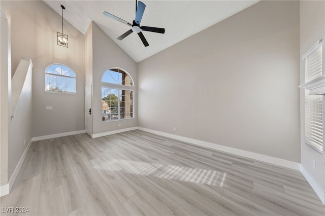 interior space with ceiling fan with notable chandelier, light hardwood / wood-style floors, and high vaulted ceiling