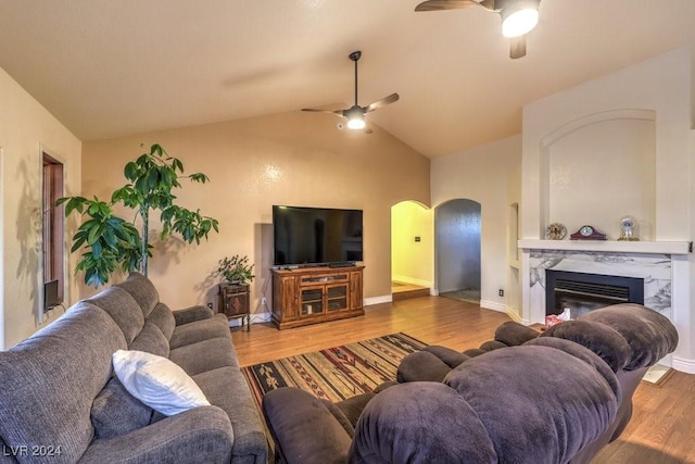 living room with a high end fireplace, hardwood / wood-style floors, vaulted ceiling, and ceiling fan