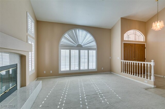 entryway with light colored carpet, a high end fireplace, and a chandelier